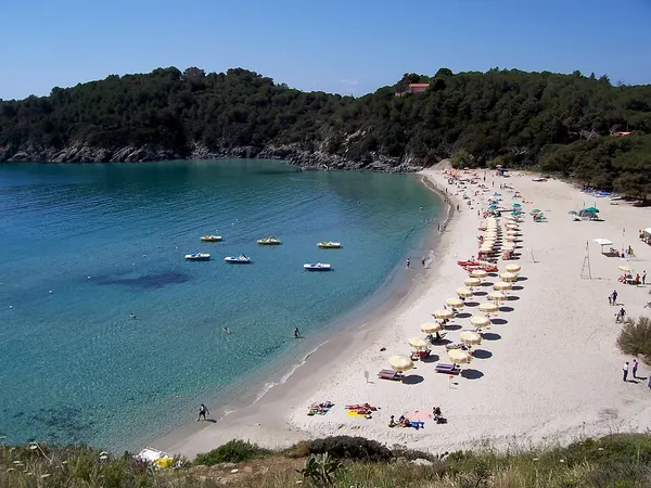 La spiaggia di Fetovaia vista dall’alto, con la baia e gli ombrelloni lungo la riva.